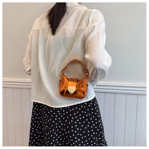 Détail du mini sac orange laser avec fermoir coeur doré et bandoulière chaîne