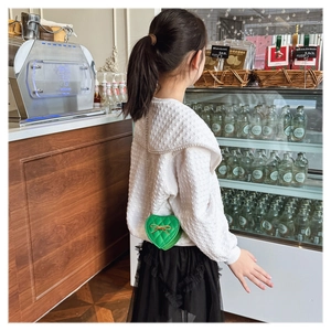 Close-up of green heart-shaped quilted handbag with a golden bow and chain strap