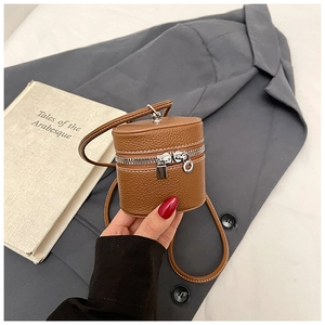 Detail shot of brown litchi pattern mini bucket bag with silver zipper and slim strap