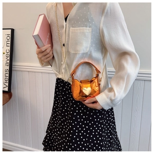 Détail du mini sac orange miroir avec fermoir cœur et chaîne dorée sur mannequin