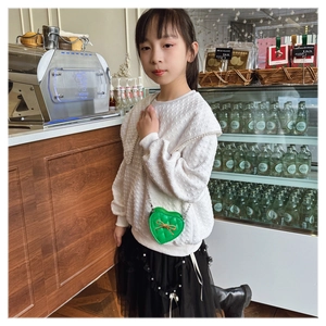 Detail of lime green heart shaped crossbody bag with quilted pattern and gold bow charm