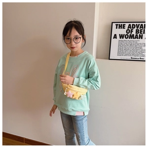 Détail d'un sac de poitrine jaune pour enfants avec trois étoiles en peluche et sangle ajustable