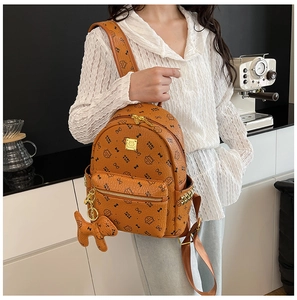 Détail d'un sac à dos en similicuir marron avec motifs de chats, lettres et rivets