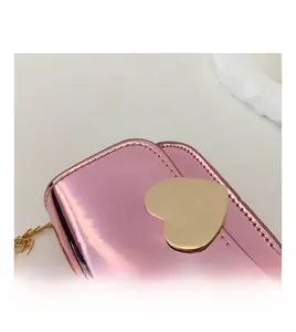 Detail of pink mirror-finish mini bag with gold heart clasp and metal chain strap