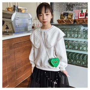 Detail of girls' outfit featuring a green heart quilted bag and pearl beaded collar