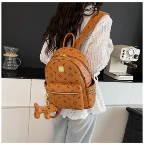 Détail d'un sac à dos en similicuir marron avec imprimés chats et breloque chien