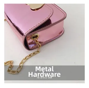 Macro shot of pink glossy crossbody bag featuring golden heart hardware and chain details