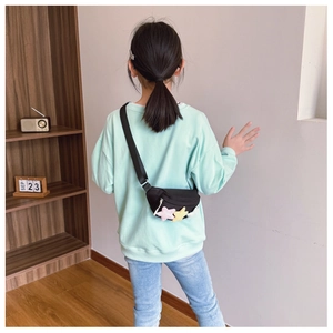 Sac de poitrine noir pour enfant avec étoiles en peluche colorées porté par un enfant
