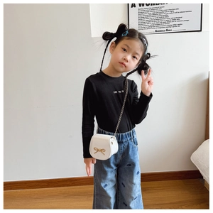 Look moda bimba con borsa bianca con fiocco e jeans larghi con ricami a fiocco blu