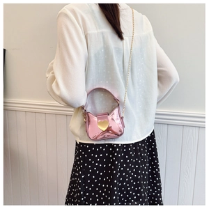 Détail du mini sac laser rose avec fermoir cœur et chaîne porté par un modèle