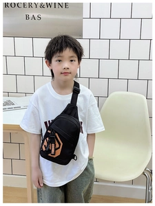 Detail view of boys' black crossbody bag featuring orange geometric patterns and brand strap