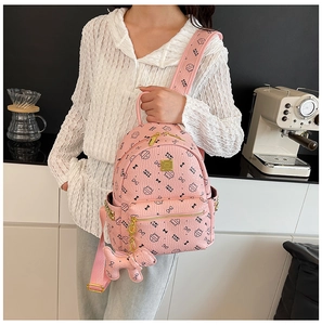 Détail du mini sac à dos rose avec imprimé chat, clous dorés et breloque chiot