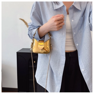Détail d'un mini sac doré brillant avec boucle en cœur et bandoulière en chaîne