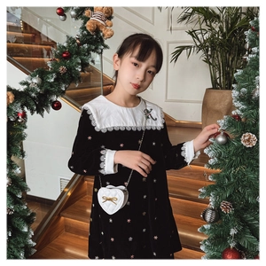 Detail of a velvet kids dress with lace collar and a heart-shaped quilted chain bag