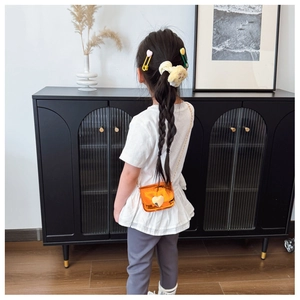 Back view of child model wearing a mini bright orange crossbody bag with heart clasp