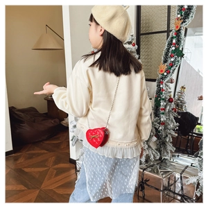 Detail of red heart-shaped girls crossbody bag with gold bow and quilting in Christmas scene