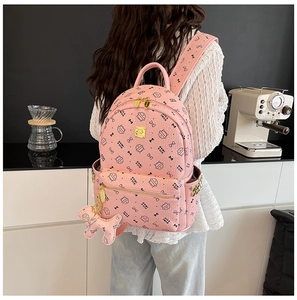 Sac à dos rose avec imprimés de chats et pendentif chiot porté par un mannequin en cuisine