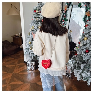Detail view of a child's heart-shaped red quilted crossbody bag with a gold bow accent