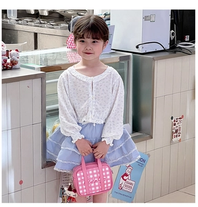 Pink checkered kids mini handbag with cute cartoon pendant shown in a lifestyle scene