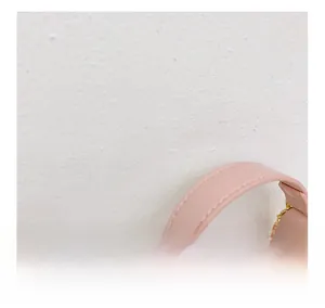 Gros plan de la poignée en cuir rose avec coutures soignées et fermeture éclair en métal doré