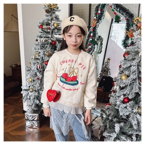 Close-up of a child's white cherry pie sweatshirt with a red heart-shaped crossbody bag