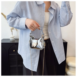 Vue détaillée du mini sac argenté laser avec chaîne dorée et fermoir en cœur