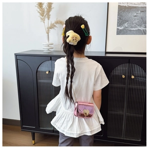Close-up of kids heart crossbody bag with plush bear scrunchie and hair clips