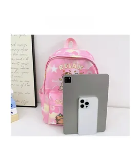 Pink cartoon school backpack shown next to tablet and phone to demonstrate large capacity size