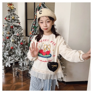 Detailed close-up of girls cream sweatshirt featuring lace hem and cherry illustration