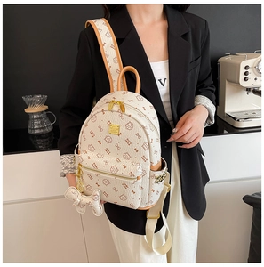 Détail d'un mini sac à dos blanc avec motifs de chat et ferrures dorées sur un mannequin