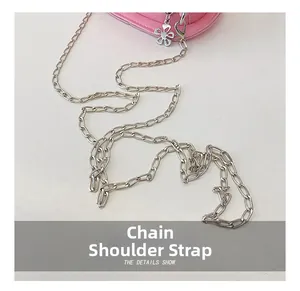 Detail of pink crossbody bag featuring silver chain strap and flower charm pendant