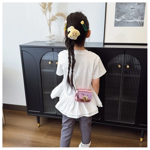 Pink metallic crossbody bag with gold heart clasp shown on a child model's shoulder