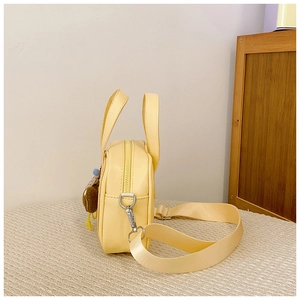 Detail of yellow mini square bag with adjustable strap and plush bear charm