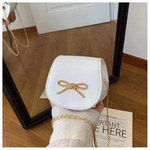 Dettaglio della mini borsa bianca lucida con fiocco dorato e tracolla a catenella