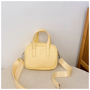Detail of yellow PU leather mini handbag showing top handles and adjustable strap