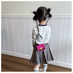 Detail of rose pink metallic mini crossbody bag with heart buckle on a child model