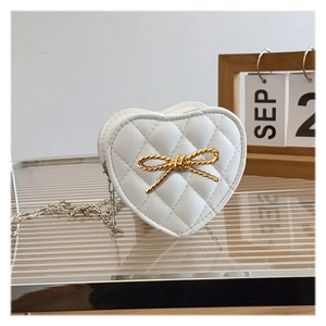 Detail of white heart-shaped crossbody bag with diamond quilting and golden bow buckle