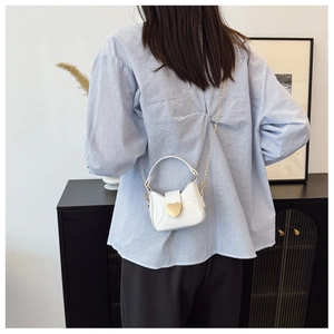 Vue détaillée d'un mini sac blanc en cuir verni avec fermoir cœur doré et chaîne