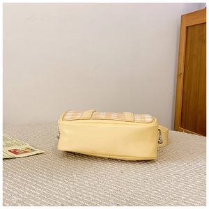 Detail shot of yellow checkered mini handbag showing base and side metallic ring