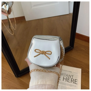 Dettaglio della mini borsa metallizzata argento con fibbia a fiocco dorato e catenella