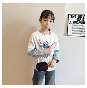 Detail of a girl wearing a black quilted chain crossbody bag with a diamond stitch pattern