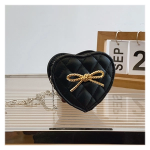 Close-up of heart-shaped quilted leather girls bag with gold bow knot and silver chain
