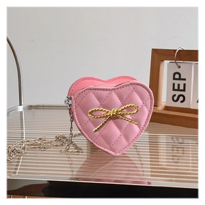 Close-up of pink heart-shaped quilted handbag with metallic bow detail and chain strap