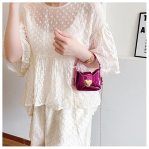Détail du mini sac violet brillant avec fermoir coeur doré et chaîne en métal sur modèle