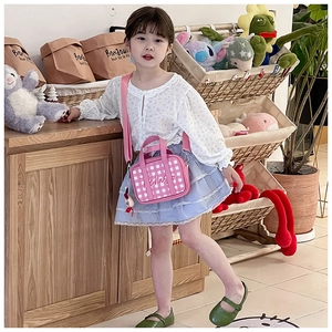 Pink checkered kids crossbody bag with adjustable strap and cute pendant shown on a child