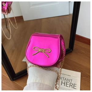 Dettaglio di una mini borsa a tracolla rosso rosa laser con fiocco dorato