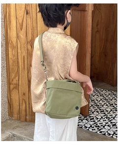Olive green canvas crossbody bag for kids shown from a stylish side view angle