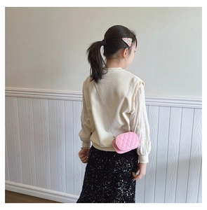 Rear view of a child wearing a pink quilted oval crossbody bag with a metal chain strap
