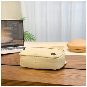 Detail of cream canvas crossbody bag for kids with black zipper on wooden table