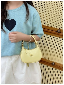 Détail du mini sac demi-lune jaune pâle avec chaîne dorée et texte en relief